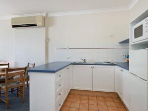 eine Küche mit weißen Schränken und einer blauen Arbeitsplatte in der Unterkunft Calypso Plaza Resort Unit 146 in Gold Coast + 11 Fotos