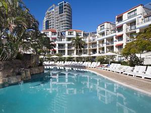 ein Pool mit weißen Stühlen und ein Gebäude in der Unterkunft Calypso Plaza Resort Unit 146 in Gold Coast
