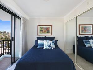 a bedroom with a blue bed and a balcony at Calypso Tower Unit 807 in Gold Coast