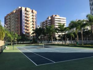 a tennis court with palm trees and buildings at Boulevard Riviera Flat - VISTA MAR E CLUBE in Riviera de São Lourenço