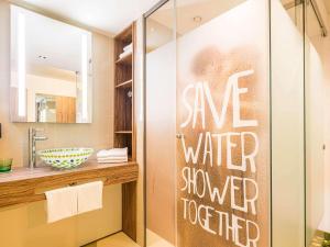 a bathroom with a glass shower door with the words save water snowrocket at Ibis Styles Wien City in Vienna