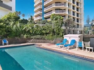 una piscina con due sedie blu e un edificio di Carool Unit 25 a Gold Coast