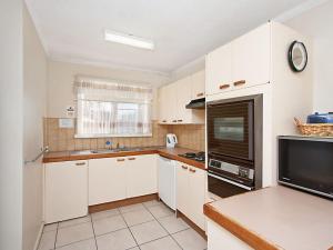 a small kitchen with white cabinets and a television at Como Unit 5 in Gold Coast
