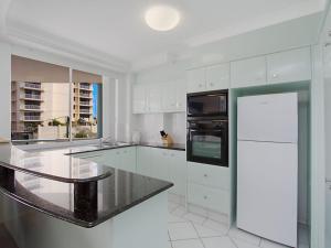 a kitchen with white cabinets and a black counter top at Classique Unit 3 in Gold Coast