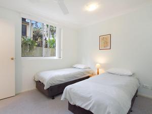 two beds in a white room with a window at Classique Unit 3 in Gold Coast