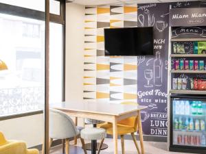 d'une salle à manger avec une table et une télévision murale. dans l'établissement Ibis Styles Paris Crimée La Villette, à Paris