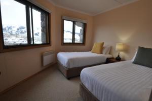 a hotel room with two beds and two windows at Salzburg Apartments in Perisher Valley