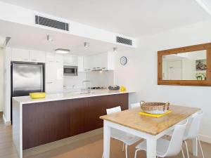 - une cuisine avec une table en bois et des placards blancs dans l'établissement Eden Apartments Unit 901, à Gold Coast