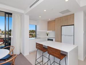 a kitchen with a white counter and a table and chairs at Iconic Apartments 704 in Gold Coast
