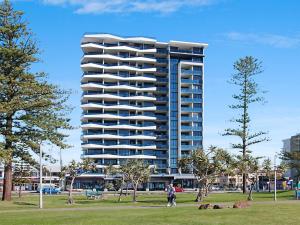 a tall building with people walking in a park at Iconic Apartments 704 in Gold Coast +10 photos