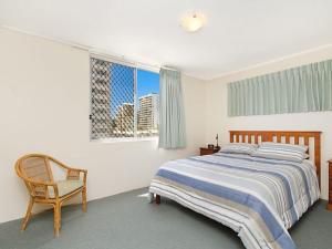 ein Schlafzimmer mit einem Bett, einem Stuhl und einem Fenster in der Unterkunft Kingston Court Unit 11 in Gold Coast