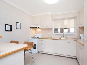 a white kitchen with white cabinets and a table and chairs at Mavic Court Unit 4 in Gold Coast