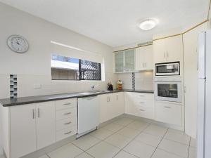 a kitchen with white cabinets and a clock on the wall at Maybury Unit 1 in Gold Coast