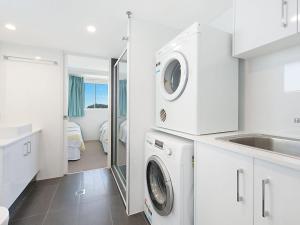 a white kitchen with a washing machine and a sink at Ocean Plaza Unit 936 in Gold Coast