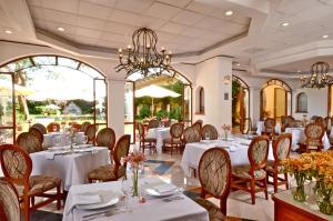 a restaurant with white tables and chairs and windows at HMB Guadalajara Centro in Guadalajara