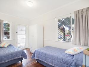 a bedroom with two beds and two windows at Tondio Terrace Flat 5 - Pet friendly and close to the beach in Gold Coast