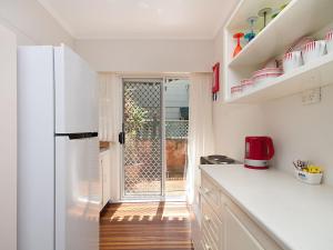 a kitchen with white cabinets and a refrigerator at Tondio Terrace Flat 5 - Pet friendly and close to the beach in Gold Coast