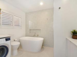 
a white toilet sitting next to a bath tub in a bathroom at Tumut Unit 2 - Great unit in a central location to beaches, clubs and shopping Wi-Fi included in Coolangatta
