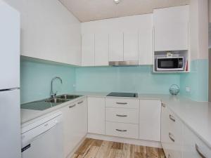 a white kitchen with a sink and a microwave at Tweed Paradise Unit 2 in Coolangatta