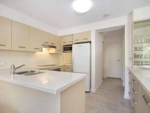 
a kitchen with white cabinets and white appliances at Woobera Unit 14 - On the hill overlooking Tweed Heads and Coolangatta in Tweed Heads
