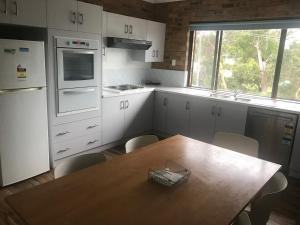a kitchen with white cabinets and a wooden table with chairs at Hawks Nest Motel in Hawks Nest