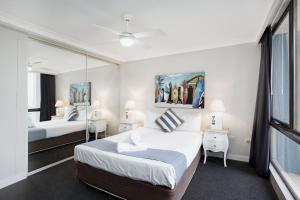 a bedroom with two beds and a mirror at Aegean Resort Apartments in Gold Coast