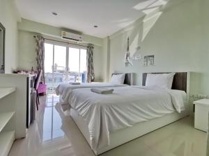 - une chambre avec un grand lit blanc et une fenêtre dans l'établissement Chevasai Hua Hin, à Hua Hin
