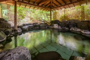una grande piscina d'acqua con rocce e alberi di Senkeien Tsukioka Hotel a Kaminoyama