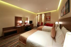 
a hotel room with two beds and a television at Al Khaleej Palace Deira Hotel in Dubai
