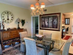 a dining room with a glass table and chairs and a clock at Island House Beach Resort 10S in Point O'Rocks