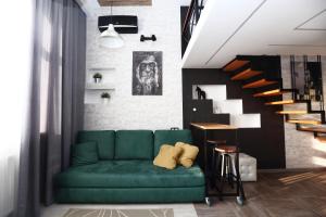 a living room with a green couch and a staircase at REHOME 24 in Tyumen