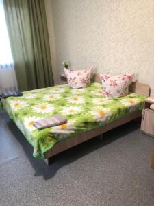 a bedroom with a bed with a flowered sheets and pillows at Hotel - Hostel Marichka in Khmilnyk