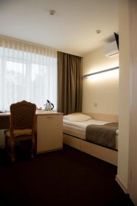 a bedroom with a bed and a desk and a window at Uyut Centralnaya Hotel in Klintsy