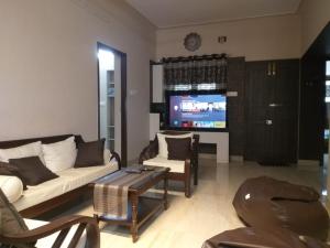 a living room with a couch and a tv at Service Apartment in Tiruchirappalli