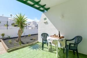 una mesa y sillas en un patio con una planta en Mimosa B1, en Puerto del Carmen