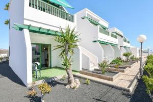 Un edificio blanco con palmeras delante. en Mimosa B1, en Puerto del Carmen