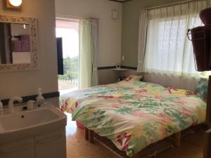 a bedroom with a bed and a sink and a window at Yakushima Pension Luana House in Yakushima