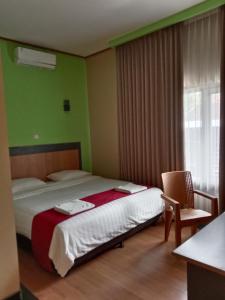 a bedroom with a bed and a chair and a window at The New Orlinds Guest House in Wonosari