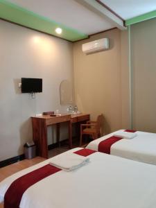 a room with two beds and a desk and a television at The New Orlinds Guest House in Wonosari