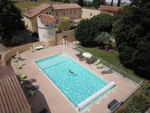 - une vue sur la piscine avec une personne qui s'y baigne dans l'établissement Le Mas des Quintrands Manosque - Motel de charme, à Manosque