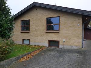 ein Backsteinhaus mit zwei Fenstern und einer Auffahrt in der Unterkunft Underetage i Dronningborgvilla in Randers