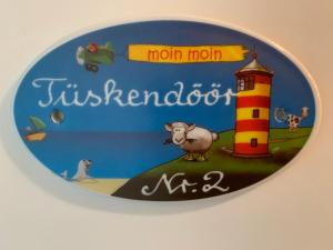 uma placa redonda com uma imagem de um farol e uma ovelha em Suite Hotel Villa Erika em Borkum