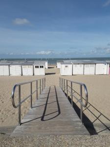 a wooden boardwalk leading to a beach with buildings at Studio spacieux 50 m2 pour 2+2 tout confort in Knokke-Heist