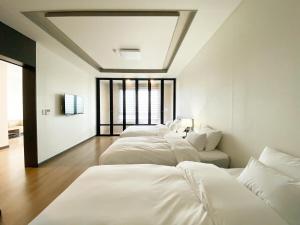 una fila de camas blancas en una habitación en Hotel Daoom en Ulsan