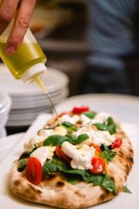 a person drizzling sauce onto a pizza on a plate at Le Lanterne in Borgo San Dalmazzo