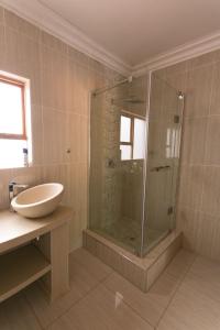 a bathroom with a glass shower and a sink at Ein Gedi Premier Lodge in Kimberley