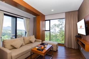 a living room with a couch and a tv at Swiss-Belresort Dago Heritage in Bandung