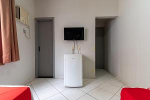a room with a refrigerator and a tv on the wall at Viareggio Hotel - Niteroi in Niterói