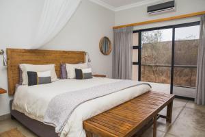 a bedroom with a large bed and a window at Manzini River House in Hectorspruit