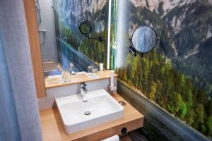 a bathroom with a sink and a mirror at TUI BLUE Montafon in Schruns +53 photos